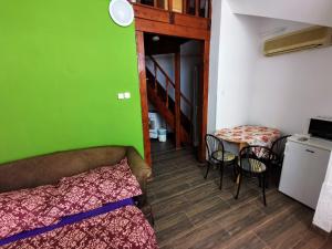 a room with a green wall and a bed and a table at Napospart 32 in Balatonlelle