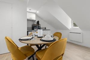 a dining room with a table and yellow chairs at Pomme rouge in Saint-Quentin