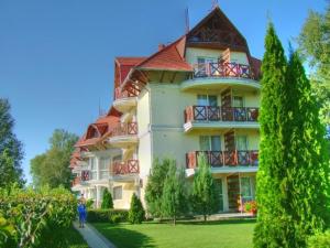 a large building with balconies and a person walking in front of it at Napospart 32 in Balatonlelle