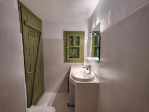 a bathroom with a sink and a green door at Thymariá - Chora view house in Chora Folegandros