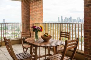 a wooden table with a bowl of fruit on a balcony at Bermondsey Apartments By Sleepy Lodge in London