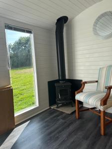 a room with a stove and a chair and a window at Secret Valley Shepherds Hut in Llanfaenor