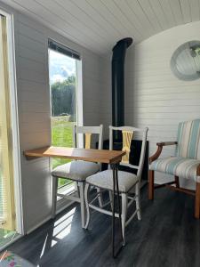 a dining room with a table and chairs and a window at Secret Valley Shepherds Hut in Llanfaenor