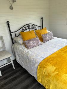a bed with pillows and a chair in a bedroom at Secret Valley Shepherds Hut in Llanfaenor