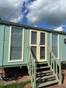 a green mobile home with a porch and stairs at Secret Valley Shepherds Hut in Llanfaenor