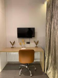 a desk with a chair and a television on a wall at The Lux Supernova in New Delhi