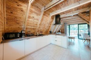 cocina con armarios blancos y techo de madera en Ośrodek Wypoczynkowy Nad Leśną Wodą, en Bystrzyca