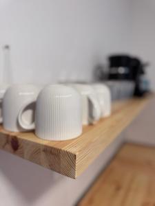 a row of white coffee cups sitting on a counter at Rybka living apartments in Přerov