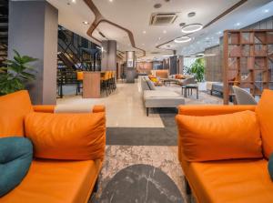 an office lobby with orange couches and tables at Holiday Inn Rosario by IHG in Rosario