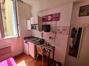 a small pink kitchen with a table and a sink at Studio Girodeau Moulins in Moulins