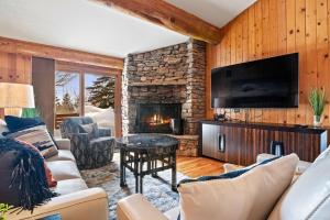 a living room with a fireplace and a stone wall at RMR: Eagles Rest 10 Condo in Teton Village in Teton Village