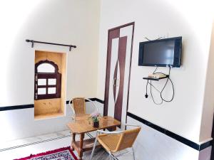 a room with a table and chairs and a tv on a wall at Ideal Guest House in Jaisalmer