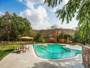 a swimming pool with tables and chairs in a yard at Dev Bagh Luxurious Private Suites in Debāri