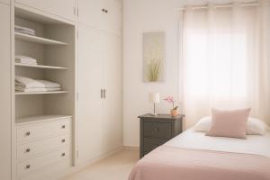 a white bedroom with a bed and a dresser at Apartamento sureño in Cádiz