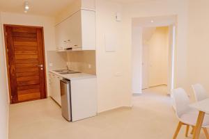 una cocina con electrodomésticos blancos, mesa y sillas en Phaedrus Living Seaside Thalassa Cretan 103, en Módhion 5 fotos más