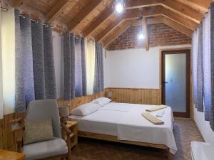a bedroom with a white bed and a chair at Boutique Vila ERI in Gjirokastër