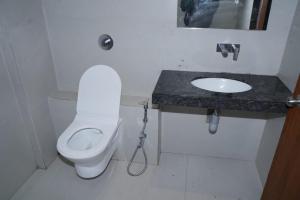 a bathroom with a white toilet and a sink at Hotel Yashraj Regency in Sangamner