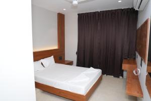 a bedroom with a white bed and a black curtain at Hotel Yashraj Regency in Sangamner