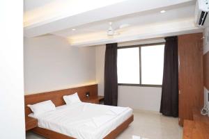 a bedroom with a white bed and a window at Hotel Yashraj Regency in Sangamner +2 photos