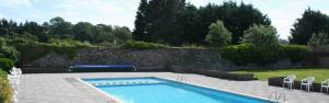 a swimming pool in a yard next to a stone wall at Ants Hill Holiday Home in Laugharne