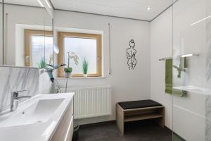 a white bathroom with a sink and a mirror at Ferienwohnung Janko in Meßstetten +16 photos