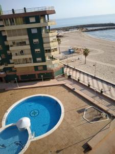 ein Schwimmbad neben einem Strand und einem Gebäude in der Unterkunft Apartamento entero Playa Perello Valencia in El Perelló + 8 Fotos