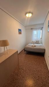 ein Schlafzimmer mit einem Bett in einem Zimmer mit einem Fenster in der Unterkunft Apartamento entero Playa Perello Valencia in El Perelló