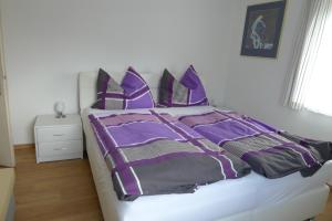a bed with purple and black sheets and pillows at Ferienwohnung Kusternik in Velden am Wörthersee