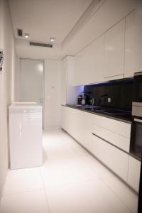 een witte keuken met witte kasten en een spoelbak bij Elegant 2- bedroom in heart of Talatona in Belas
