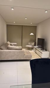 een woonkamer met een bed en een televisie bij Elegant 2- bedroom in heart of Talatona in Belas