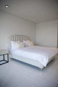 een witte slaapkamer met een groot bed met witte lakens bij Elegant 2- bedroom in heart of Talatona in Belas +17 foto's