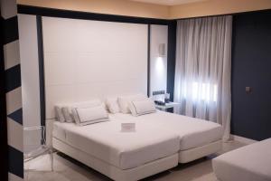 a bedroom with a large white bed with white pillows at Hotel Málaga Nostrum Airport in Málaga