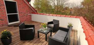 a patio with chairs and a table on a deck at Ferienwohnung Lütje Moew - Dachterrasse und ruhige Lage in Leezdorf