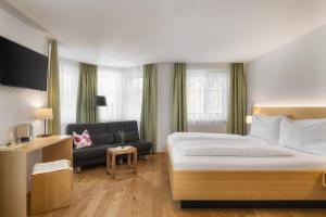 a hotel room with a bed and a couch at OXA - Easy Escape - Bed & Breakfast in Hittisau