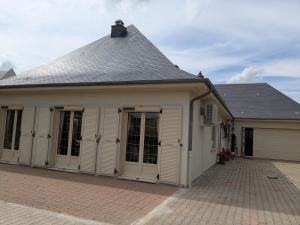 a building with white doors and a roof at Gîte des Lilas in Stenay