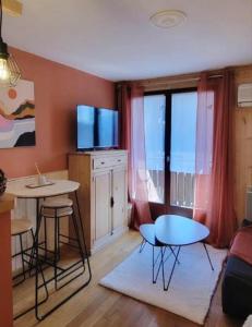 un salon avec une table et une télévision dans l'établissement Appartement avec balcon vue montagne à Bellevaux, à Bellevaux