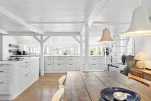 a kitchen with white cabinets and a wooden table at 3075-Stege-Kullegardsvej-35 in Stege