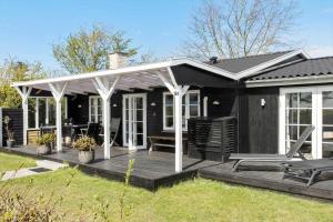 a black house with a porch and a deck at 8207-Vordingborg-Strandparken-22 in Vordingborg