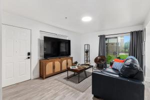 a living room with a black couch and a flat screen tv at UF Apartment on Archer Road Near Shands & VA ! in Gainesville