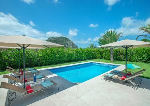 einen Pool mit zwei Sonnenschirmen und zwei Stühlen sowie einem Pool in der Unterkunft Owl Booking Villa Divina - Luxury Retreat in Pollença