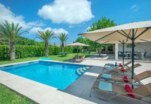 ein Schwimmbecken mit Stühlen und einem Sonnenschirm in der Unterkunft Owl Booking Villa Divina - Luxury Retreat in Pollença