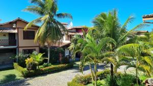 a house with palm trees in front of it at Casa 4 Quartos 2 Quadras da Praia Com Roupa Cama in Porto Seguro
