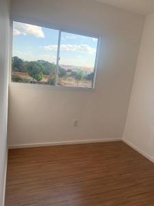 an empty room with a large window and a wooden floor at Apartamento Centro oeste aguas lindas in Macacos