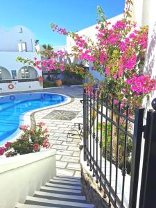 a fence with pink flowers next to a swimming pool at New Haroula in Fira