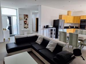 a living room with a black couch and a kitchen at Le petit plaisir des caves in Dormans