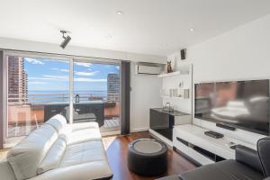 een woonkamer met een witte bank en een grote tv bij Stunning Renovated 1-Bedroom Breathtaking View in Beausoleil