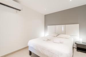 een witte slaapkamer met een wit bed en 2 handdoeken bij Stunning Renovated 1-Bedroom Breathtaking View in Beausoleil