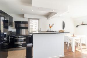 een keuken met zwart-witte apparatuur en een tafel bij Stunning Renovated 1-Bedroom Breathtaking View in Beausoleil