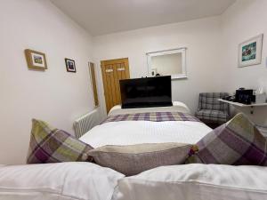 a bedroom with two beds and a tv on the wall at Carron Cottage in Inverness