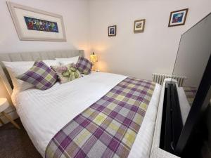 a bedroom with a bed with a quilt on it at Carron Cottage in Inverness